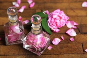 Obraz na płótnie Canvas Rose oil in bottles on color wooden background