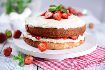 Delicious biscuit cake with strawberries on table close-up