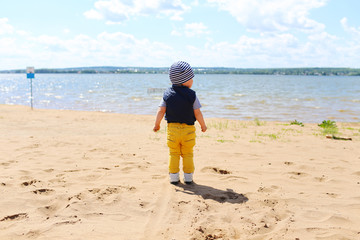 baby standing on shore of the lake