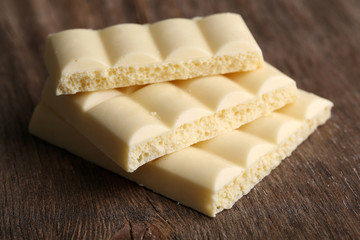 White chocolate bar on color wooden background