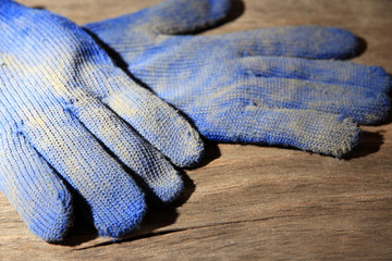 Fototapeta na wymiar Dirty used fabric gloves on wooden background