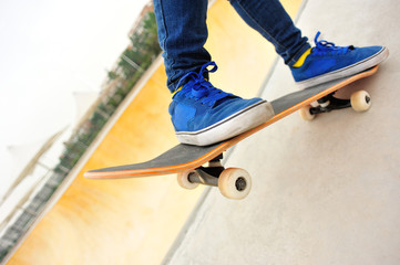 Fototapeta na wymiar woman skateboarder legs skateboarding at skatepark