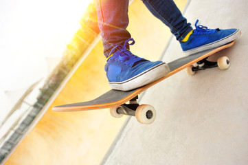 Fototapeta na wymiar skateboarding woman legs at sunrise skatepark