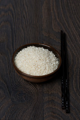 white rice in a bowl and chopsticks on dark background