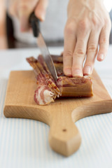 Woman's hands cutting bacon into strips, close up