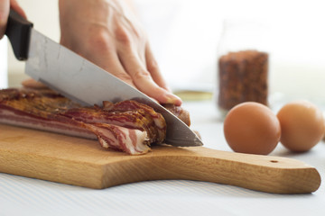 Woman's hands cutting bacon into strips, close up