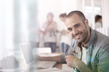 Fototapeta premium Cheerful reporter working in office on laptop