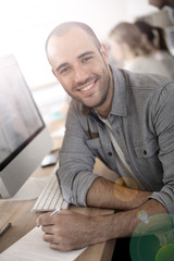 Cheerful guy sitting in front of desktop computer