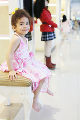 Little barefoot girl sits and smiles in children store