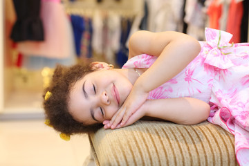 Obraz na płótnie Canvas Little pretty girl smiles and pretends to be asleep on pouf