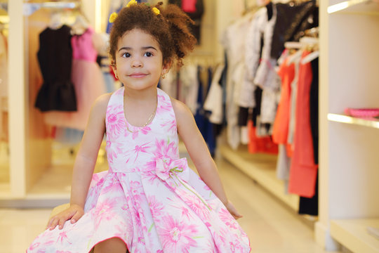 Little pretty girl in dress sits in children store
