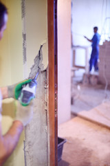 Builder works with drill near door frame in unfinished apartment