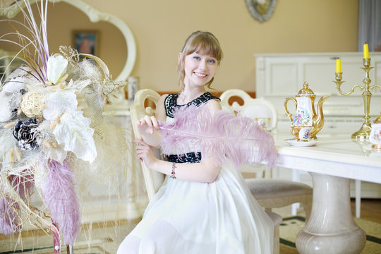 Beautiful Smiling Girl Sits At Table With Set Of Dishes