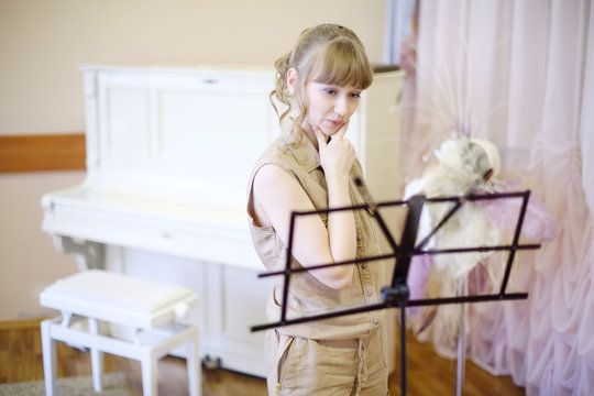 Beautiful girl stands near music stand in room