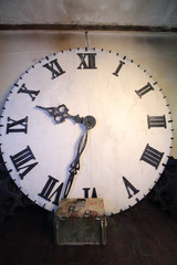 Big white clock with Roman dial stands in room