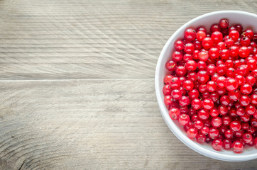 Bowl with fresh redcurrant on the wooden table