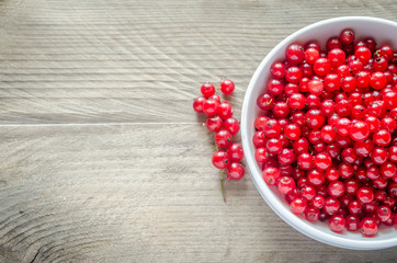 Bowl with fresh redcurrant on the wooden table