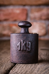 Vintage iron 1 kg weight in front of an old brick wall.