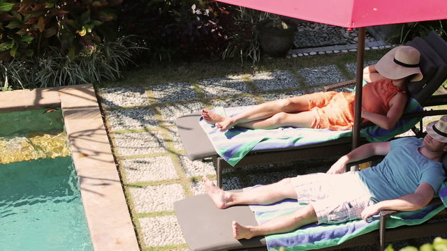 Couple sleeping on sunbeds