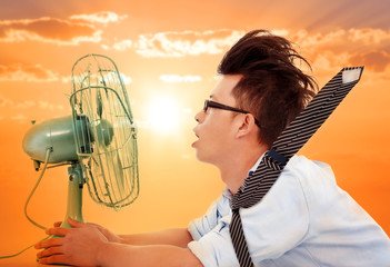 the heat wave is coming,business man holding a  electric fan - obrazy, fototapety, plakaty