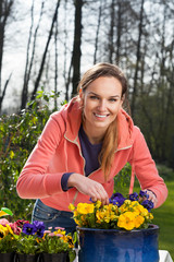 Smiling woman planting pansy flowers