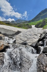 Grotto from snow over the mountain river in the summer