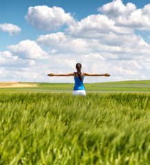 Image of a girl in a wheat field with spread arms