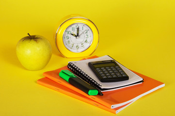 Exercise books, a notepad, calculator and apple