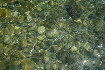 Ripples creating shadows onto round pebbles in water