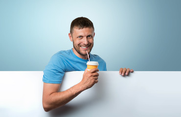 Bearded man holding a paper cup of drink with white banner