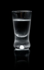 Glass of vodka isolated on black background