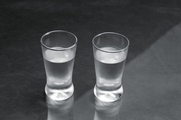 Two glasses of vodka on black marble table