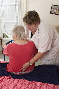 Cheerful Care Giver Helping Elderly Woman At Home