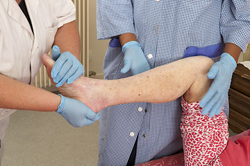 Nurse and care giver massaging foot and leg of a patient