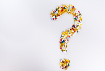 Pills as question mark on white background with copy space