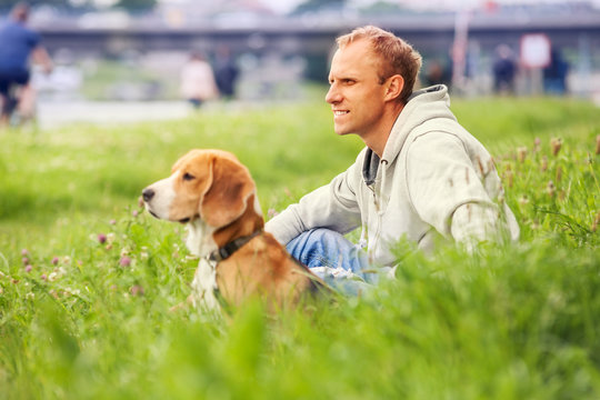 Man with his dog sitting in green grass