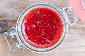 Erdbeermarmelade in einem Einmachglas auf Holz