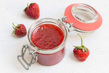 Erdbeermarmelade in einem Einmachglas auf Holz