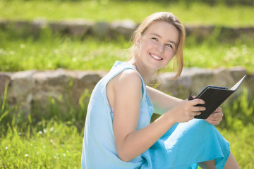 Fototapeta premium Young Happy Caucasain Girl Reading Ebook Outdoor. Positive Facia