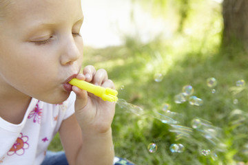 Little girl blowing bubbles outdoors