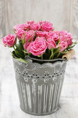 Bouquet of roses in grey decorative bucket