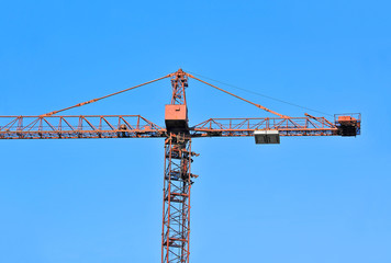 Red construction tower crane against blue sky