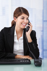 Businesswoman Using Landline Phone In Office