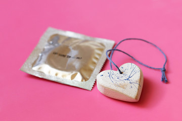 Obraz na płótnie Canvas Heart and a condom on pink background