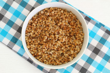 Cooked buckwheat in bowl on checkered cloth