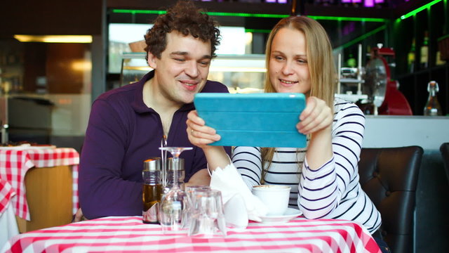 Young couple in cafe having a video chat on tablet PC
