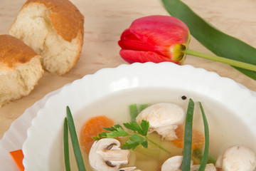 Tasty mushroom soup, slices of bread and red tulip