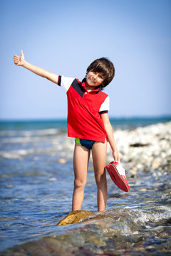 Модный мальчик с обувью на берегу моря