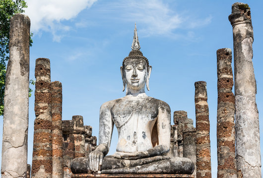 Large ancient white Buddha image and laterite pillars surround