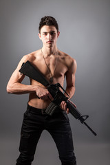 Handsome bare-chested soldier is holding a rifle